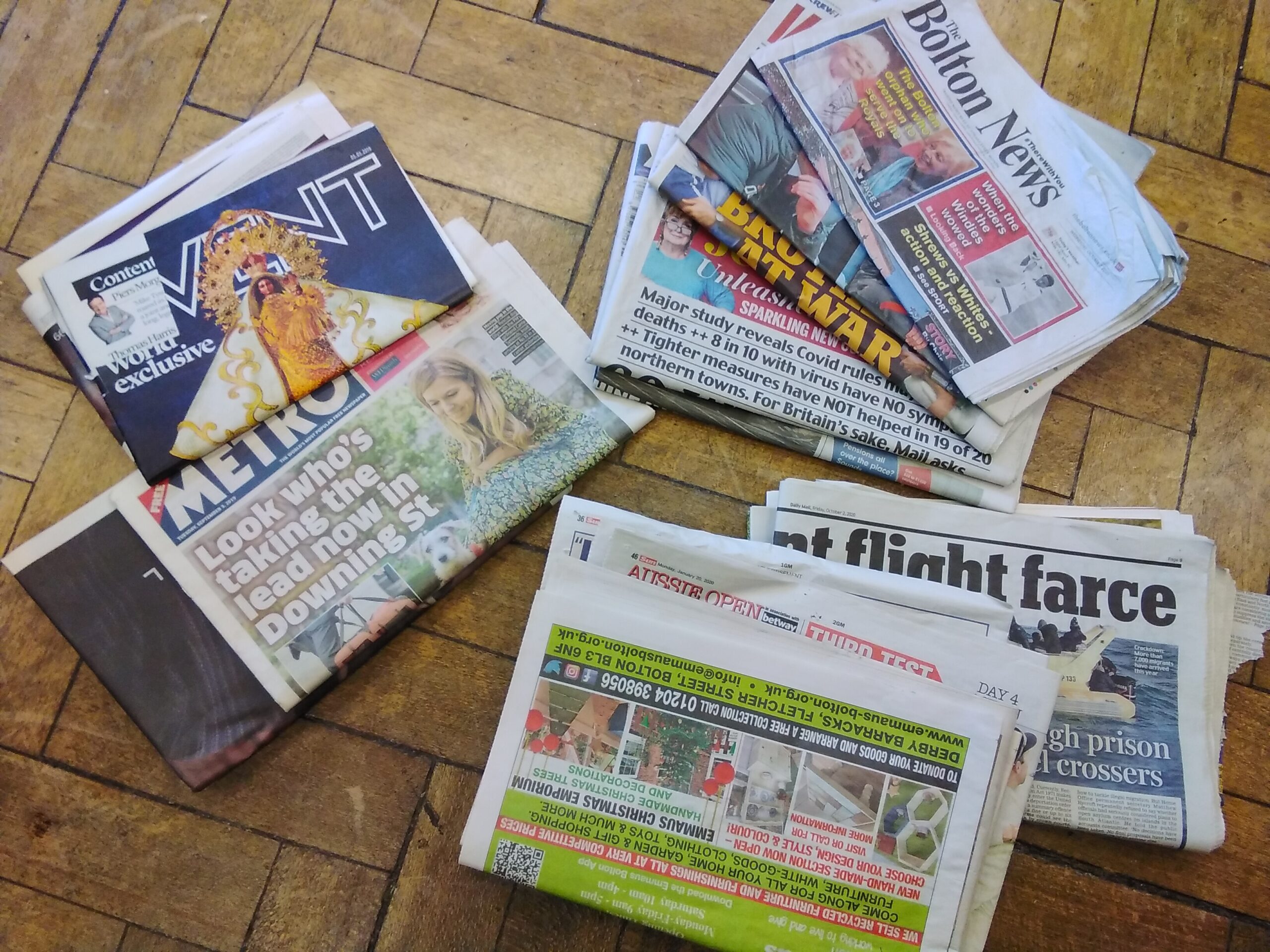 A colour photograph of a pile of newspapers scattered across the floor.