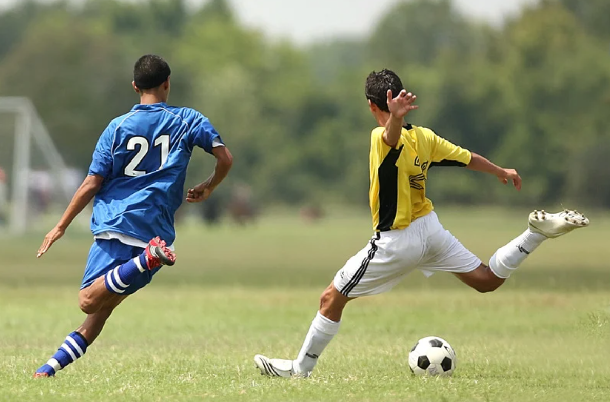 Two young adults playing football