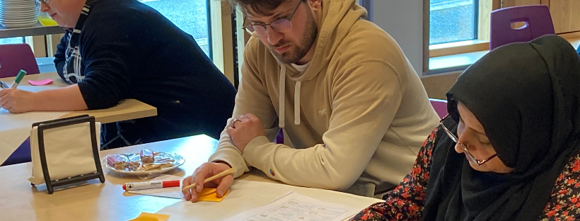 An image from one of the Community Reporter workshops. People sat a a table doing an activity.