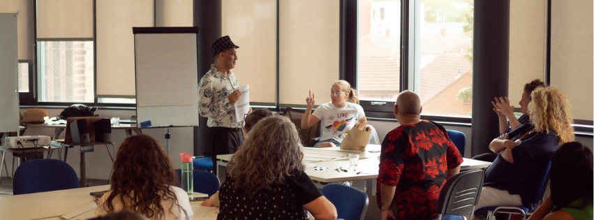 A table of people have a discussion during a conference session. People are animated and gesturing with their hands.